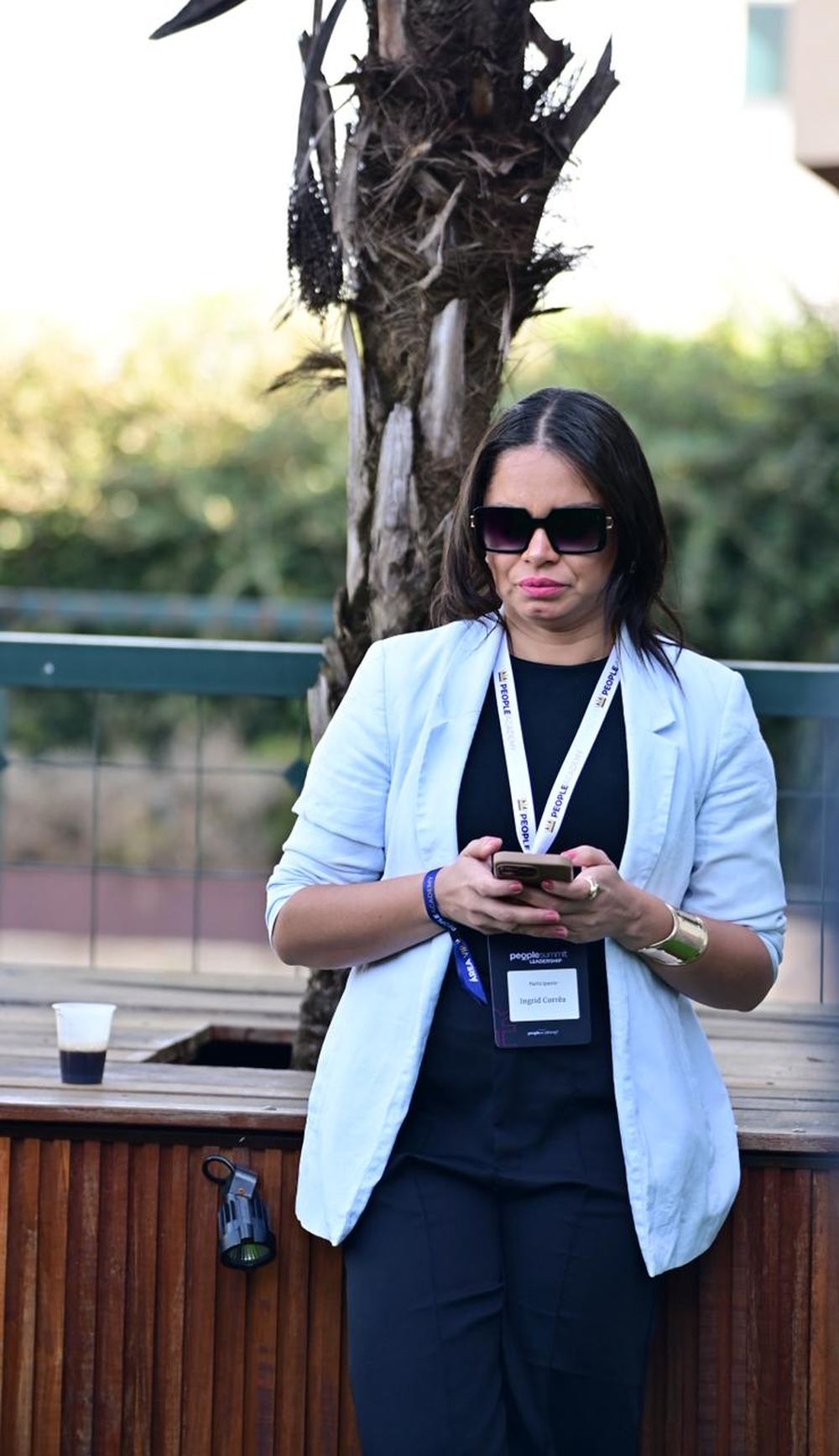 Ingrid Corrêa em pé, em ambiente externo, durante um evento profissional