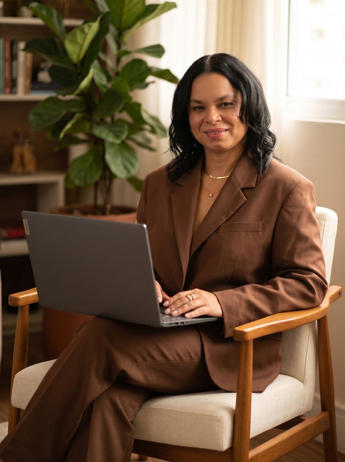 Ingrid Corrêa sentada em poltrona com o notebook no colo